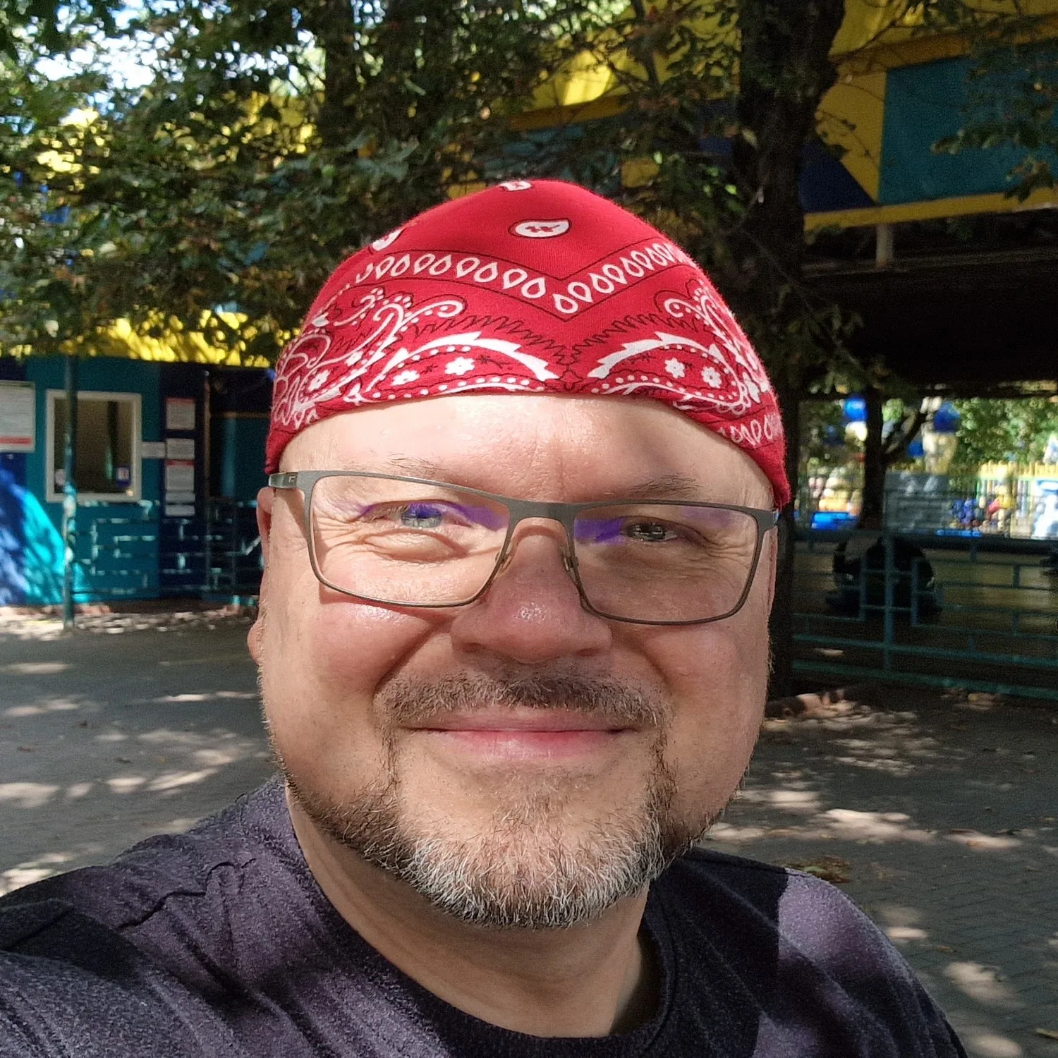 Portrait of John Loschnig, smiling, wearing a red bandana